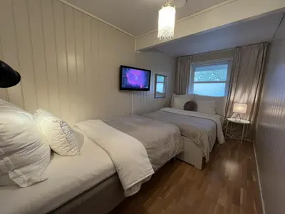 a bedroom with two beds and a tv on the wall at Bratsberg Apartment - with Kitchenette and Free Parking in Trondheim
