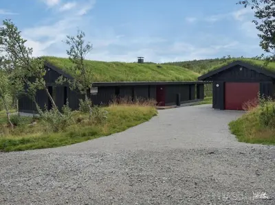 a building with a green hill on top of it at Nydelig og Moderne hytte på Kikut Geilo - 6 senger, 4 soverom og jacuzzi in Geilo