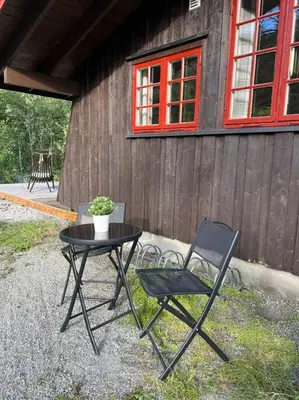 a table and two chairs in front of a building at Koselig hytte med uteplas ved Hallingdalselva in Ål
