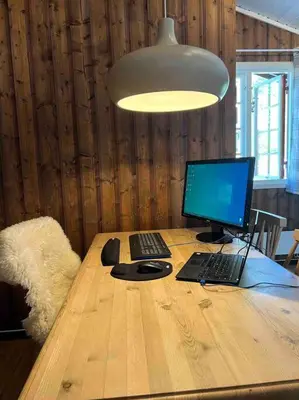 a desk with a computer and a laptop on it at Koselig hytte med uteplas ved Hallingdalselva in Ål