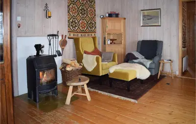 a living room with a wood stove and chairs at Awesome Home In Ustaoset With Wifi in Ustaoset