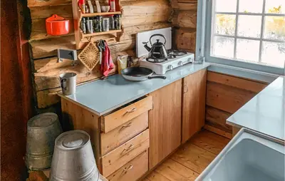 a kitchen in a log cabin with a stove at Cozy Home In Vinstra With Kitchen in Vinstra
