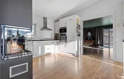 a kitchen with white cabinets and a fireplace at 3 Bedroom Awesome Apartment In Nesttun in Bergen