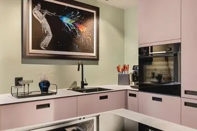 a kitchen with white cabinets and a painting on the wall at Bryggen Living in Bergen