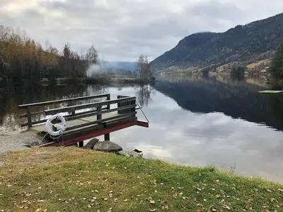 a bench sitting on the side of a lake at Delikat hytte omgitt av Hallingdals vakre fjell in Ål
