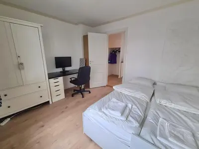 a bedroom with a bed and a desk and a chair at Fløyen Townhouse in Bergen