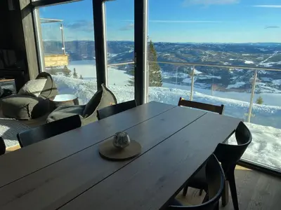 a wooden table in a room with a large window at Cosy apartment with ski in/out in Noresund