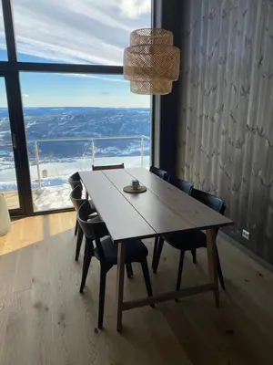 a dining room table with chairs and a large window at Cosy apartment with ski in/out in Noresund