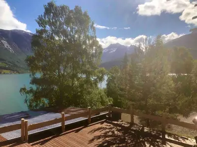 a wooden deck with a view of a lake and mountains at Olden by the fjords of Norway, Bjørkelund in Stryn