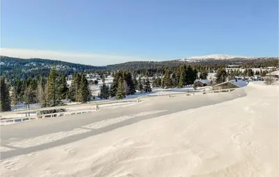 a snow covered field with a mountain in the background at Cozy Apartment In Lillehammer With Wifi in Lillehammer