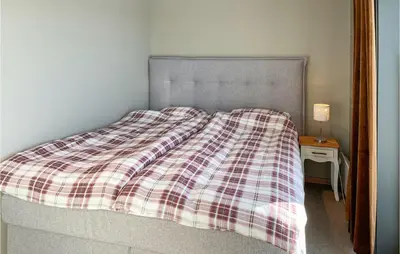a bed with a plaid blanket on top of it at Cozy Apartment In Lillehammer With Wifi in Lillehammer