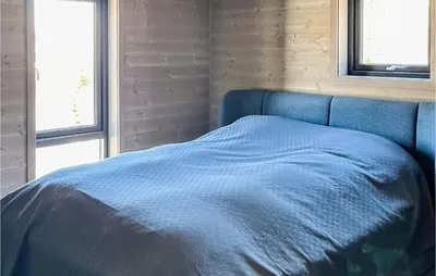 a blue bed in a room with two windows at Nice Home In Edland With Wifi