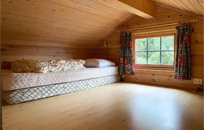 a bed in a log cabin with a window at 2 Bedroom Cozy Home In Lauvstad in Lauvstad