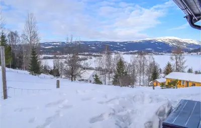 a snow covered yard with a house and mountains at Gorgeous Home In Noresund With Wifi in Noresund
