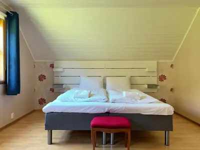 a bedroom with a large bed with a red stool at Flåm Holiday Home in Flåm