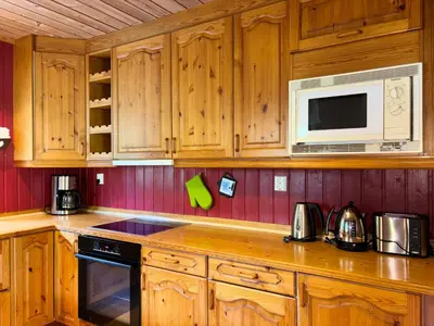 a kitchen with wooden cabinets and a microwave at Flåm Holiday Home in Flåm