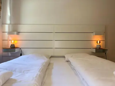 two beds in a room with two lamps on the wall at Flåm Holiday Home in Flåm
