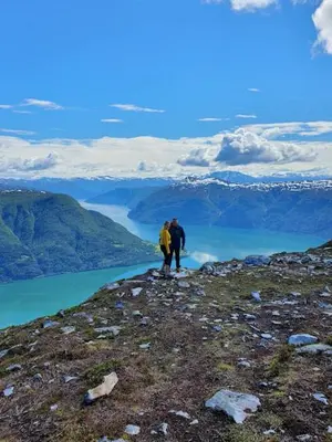 two people standing on top of a mountain overlooking a lake at Molden 2-fjellutsikt og jacuzzi tilgang. in Luster