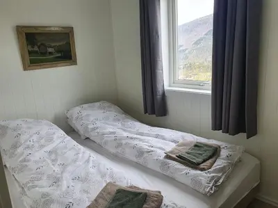 two beds in a room with a window at Molden 2-fjellutsikt og jacuzzi tilgang. in Luster