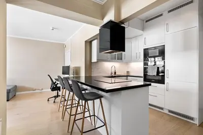 a kitchen with white cabinets and a black counter top at 2 min to Bryggen - Rooftop - Office with 49