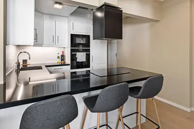 a kitchen with a black counter top and two chairs at 2 min to Bryggen - Rooftop - Office with 49