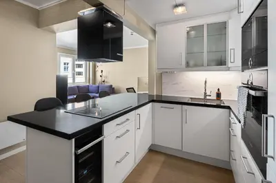 a kitchen with white cabinets and a black counter top at 2 min to Bryggen - Rooftop - Office with 49