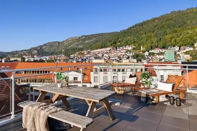 a balcony with a wooden table and benches and a city at 2 min to Bryggen - Rooftop - Office with 49