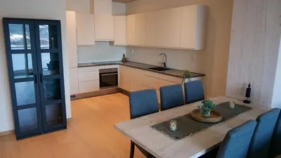 a kitchen with a wooden table and blue chairs and a table and a tableablish at MJOS TOWER Suite - Lovely lake view in Brumunddalen
