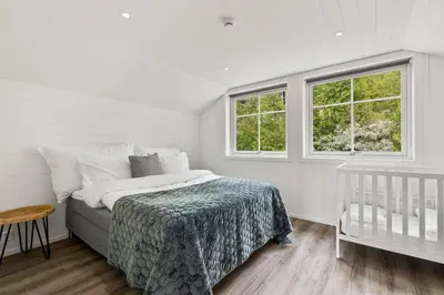 a bedroom with a bed and two windows and a crib at Grand and modern cabin in Sogndal
