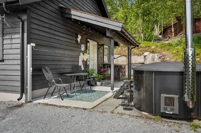 a patio with a table and a grill next to a house at Grand and modern cabin in Sogndal