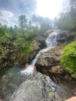 a couple of people swimming in a waterfall at Grand and modern cabin in Sogndal