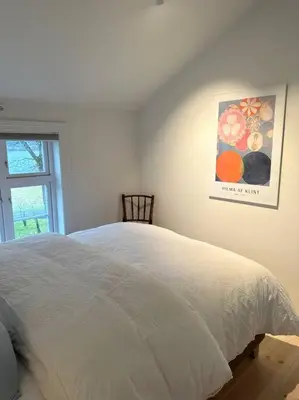 a white bed in a bedroom with a picture on the wall at Storlauvøya The Atlantic Ocean Road in Karvåg