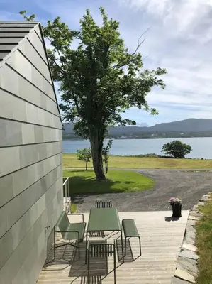 a patio with a table and chairs and a tree at Storlauvøya The Atlantic Ocean Road in Karvåg