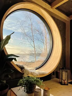 a large circular window in a room with a tree at Fuglekassehytta in Sparbu