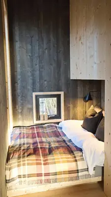 a bedroom with a bed with a wooden wall at Fuglekassehytta in Sparbu