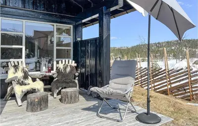two dogs sitting on a porch with a chair and an umbrella at Nice Home In Veggli With Wifi in Veggli