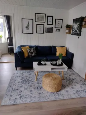 a living room with a blue couch and a coffee table at Light home apartment Alesund with free parking in Ålesund