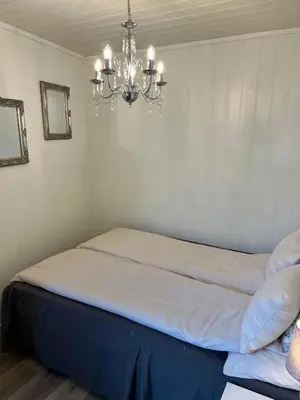 a bedroom with a bed with a chandelier at Light home apartment Alesund with free parking in Ålesund