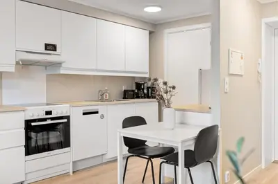 a kitchen with white cabinets and a white table and chairs at Forenom Serviced Apartments Bergen Skottegaten in Bergen