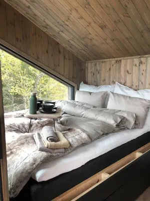 a large bed in a room with a large window at Baugsberget Fjelltopphytter in Alvdal