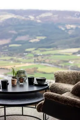 a table with bowls and cups on it next to a chair at Baugsberget Fjelltopphytter in Alvdal