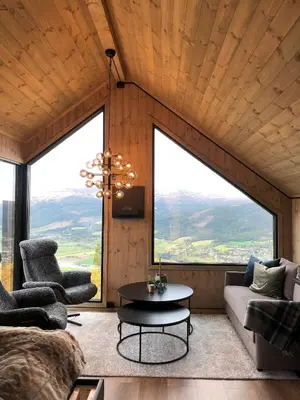 a living room with a couch and a table and large windows at Baugsberget Fjelltopphytter in Alvdal