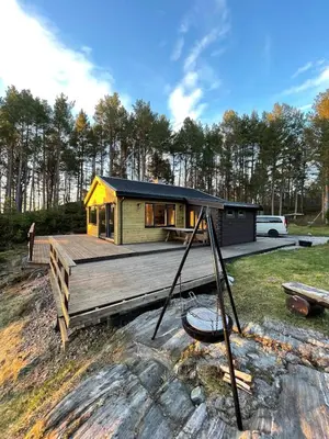 a small house on a wooden deck in front of a house at A cottage by the forest with a sea view ! in Søfstad