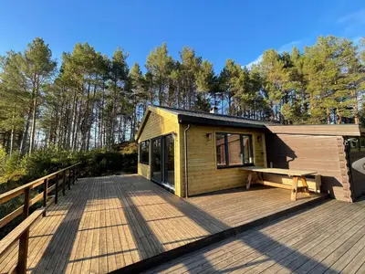 a cabin on a deck with a bench on it at A cottage by the forest with a sea view ! in Søfstad