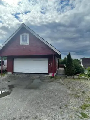 a red barn with a white garage door at Leilighet med gratis parkering og WiFi in Kristiansund