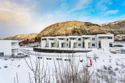 a building in the snow with a mountain in the background at Stor og moderne leilighet i Indre Arna Bergen GRATIS PARKERING!! in Bergen