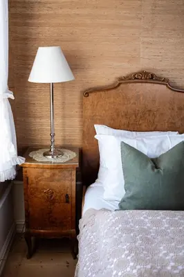 a bedroom with a bed with a lamp on a night stand at Hoel Gård - Herregården ved Mjøsa in Nes i Ådal