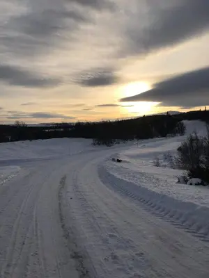 a dirt road in a snowy field with the sun setting at Cabin in the Mountain, with Solar Energy in Slidre