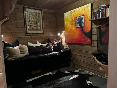 a living room with a black couch and a painting at Bjødnabakkens historie in Beitostøl