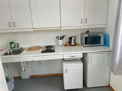 a kitchen with white cabinets and a sink and a microwave at Nye Heimen Overnatting in Namsos